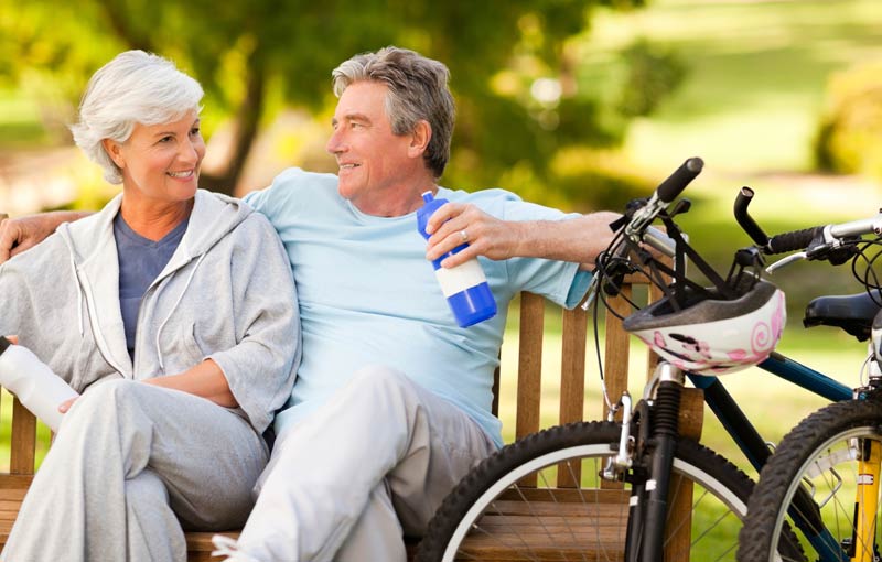 Older couple enjoying a break in the park after cycling
